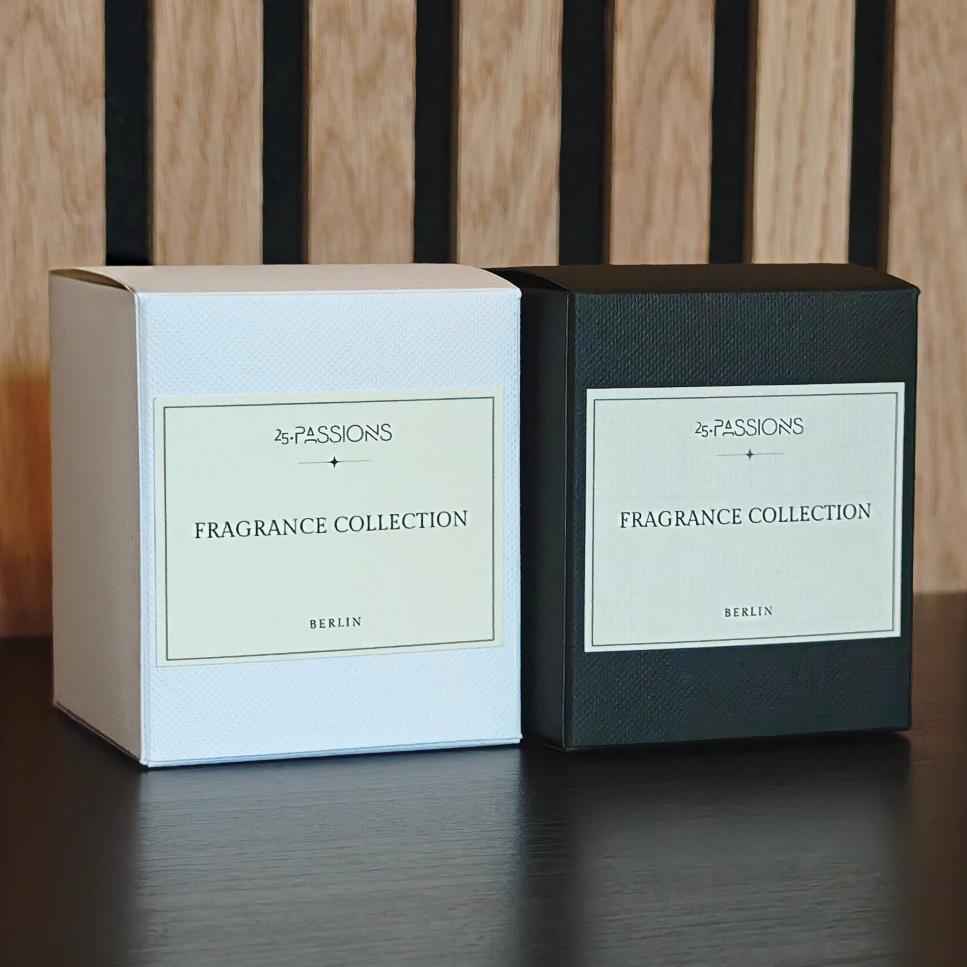 Produktverpackungen der Fragrance Collection von 25·PASSIONS in Weiß und Schwarz, nebeneinander stehend mit strukturierten Boxen und frontseitigem Etikett „Fragrance Collection · Berlin“